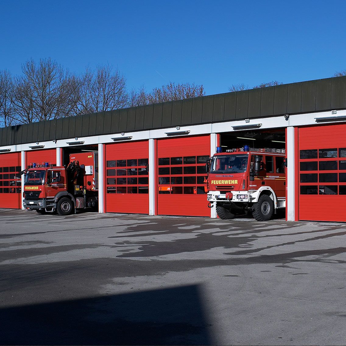 Feuerwache mit roten Sektionaltoren und Einsatzfahrzeugen