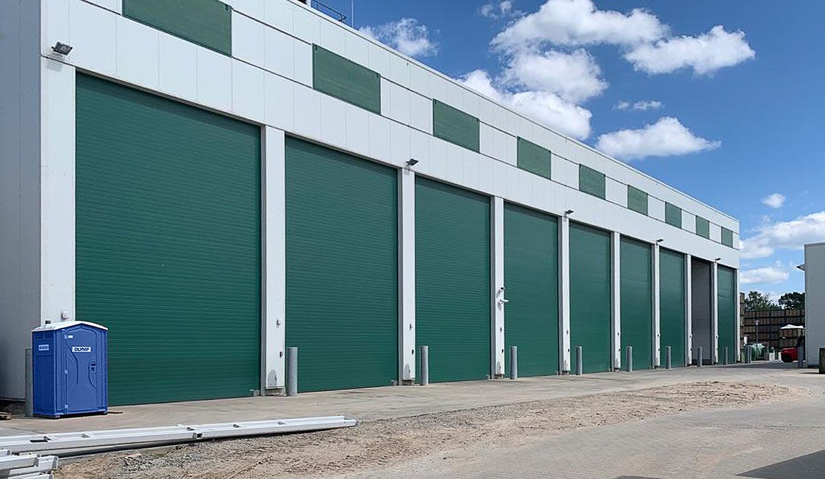 Hallenfront mit großen grünen Industrie-Sektionaltoren