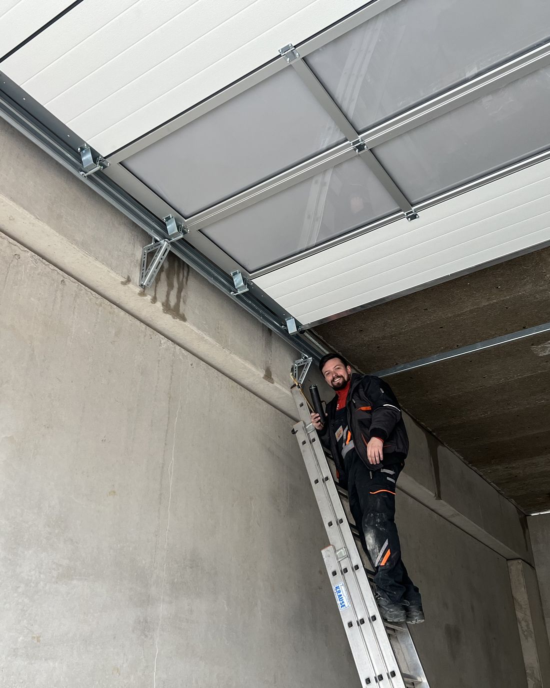 Monteur auf der Leiter bei der Montage einer Laufschiene
