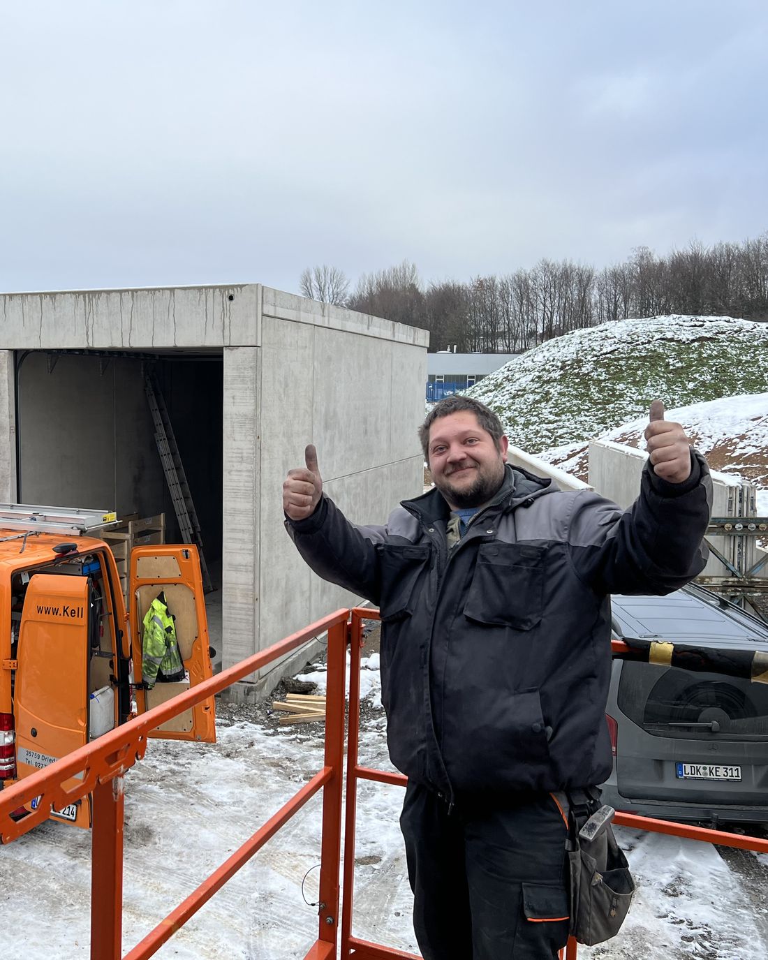 Monteur von Keller Tor-Systeme auf einer winterlichen Baustelle vor dem Montagefahrzeug